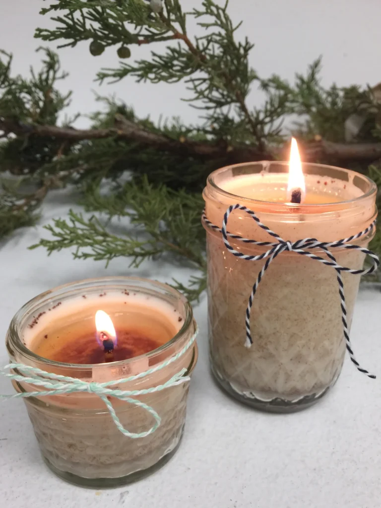 Sustainable christmas gifts: handmade candles lit and dressed in ribbon.